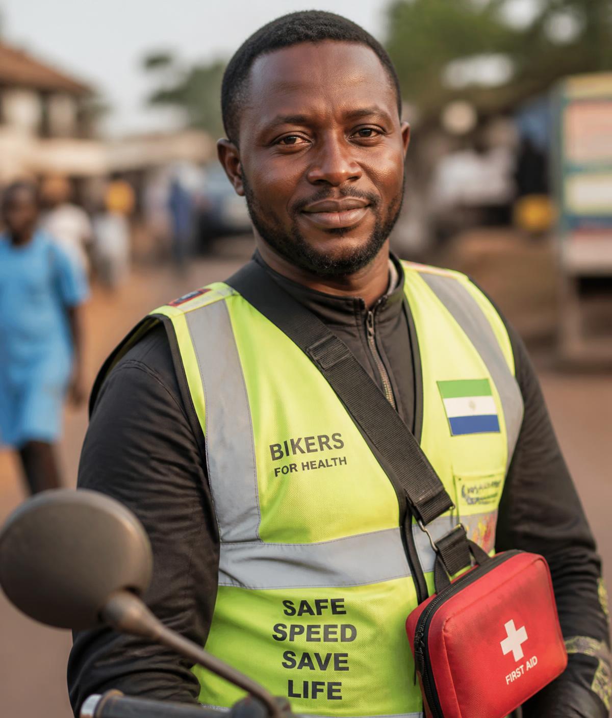 Portrait of Ibrahim, a motorcycle-taxi driver in Makeni trained as a lay first responder, wearing a reflective vest and carrying a first aid kit